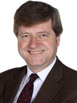 Headshot of Jonathan Odum, smiling at the camera. He is wearing a suit jacket, white shirt and tie