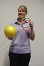 An Assistant Therapy Practitioner holding a yellow ball and large colourful rings