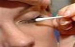image of a patient with their eyes closed using a cotton bud to clean eyes