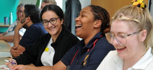 THREE GIRLS SAT AT A TABLE LAUGHING TOGETHER